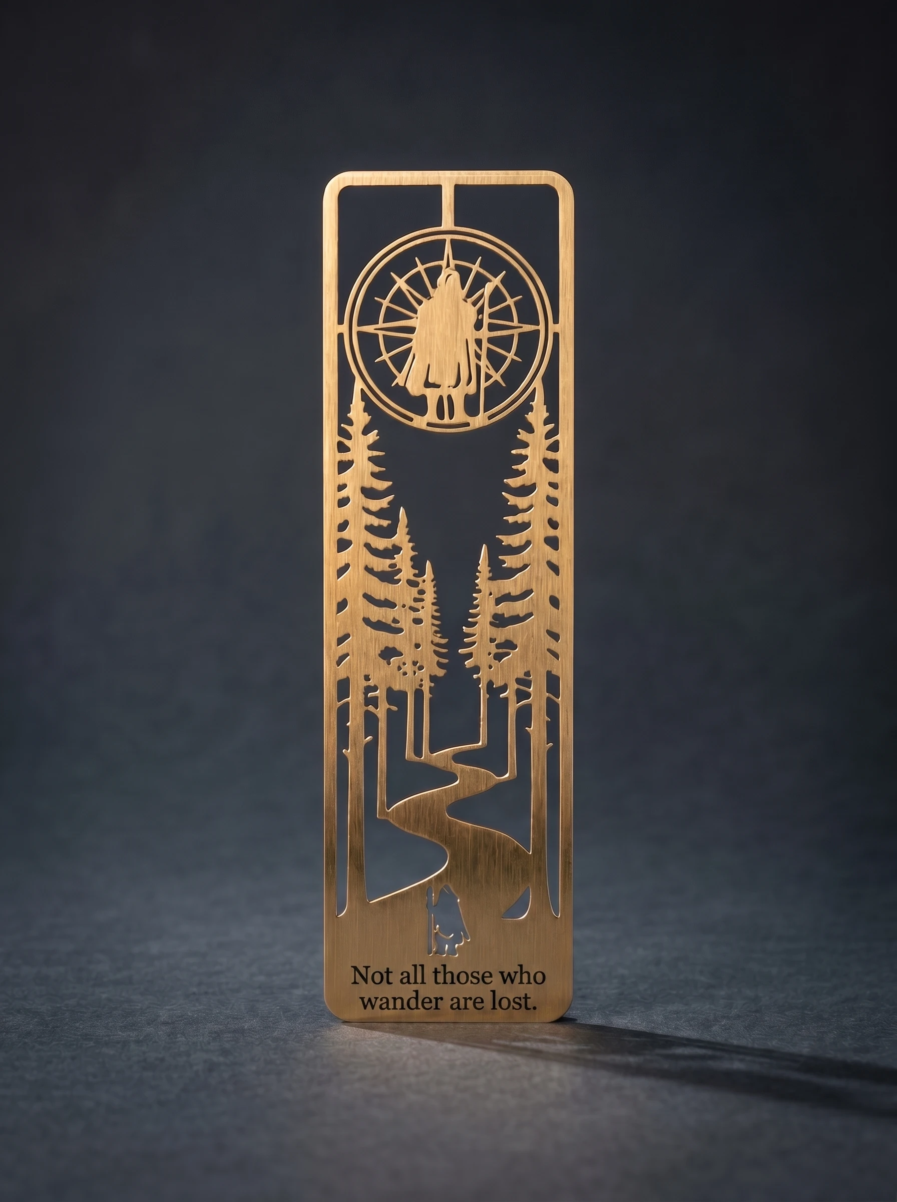 Studio product photograph of the brass bookmark against a charcoal seamless backdrop.